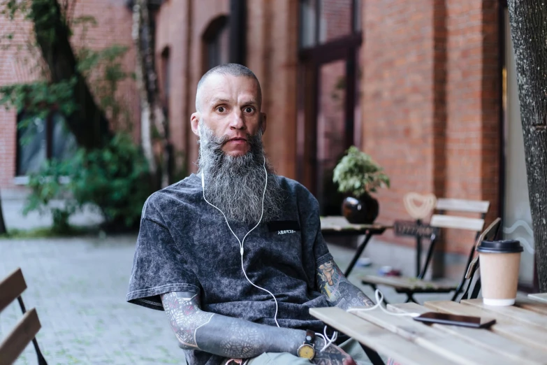 a man with a grey beard wearing headphones sitting in a restaurant bench