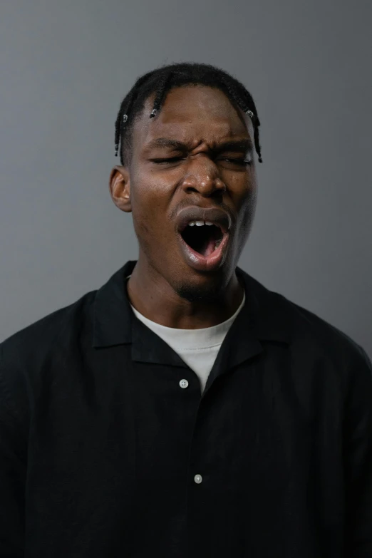 man wearing black shirt making silly expression over gray background