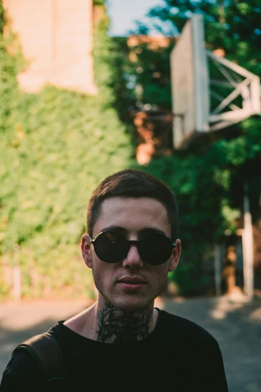 a man with dark sunglasses stands near an unpregetable basketball hoop