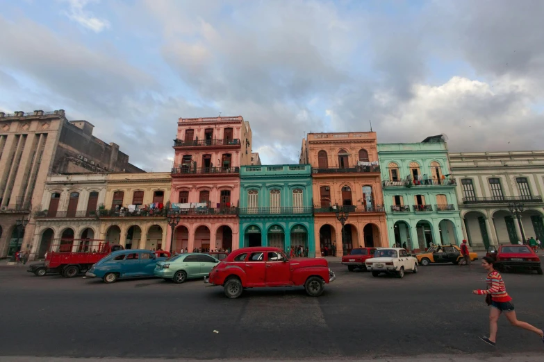 a woman crossing a road in front of many historic buildings