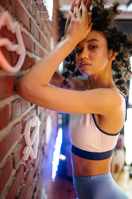 woman leaning on brick wall in sports  top and tight pants