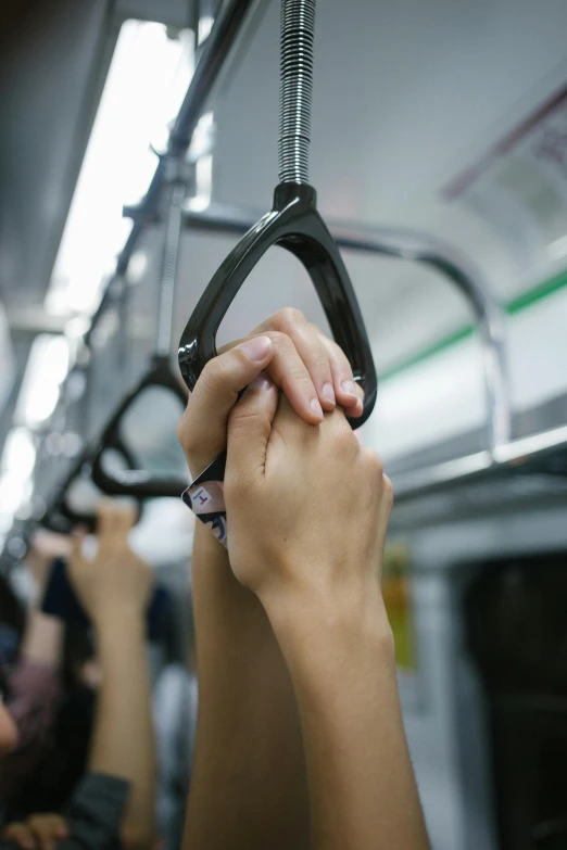 people's hands are holding onto the handle bars on a commuter train