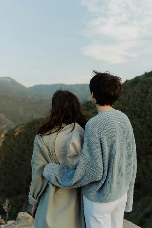 a man and woman in a beige top look over a mountain