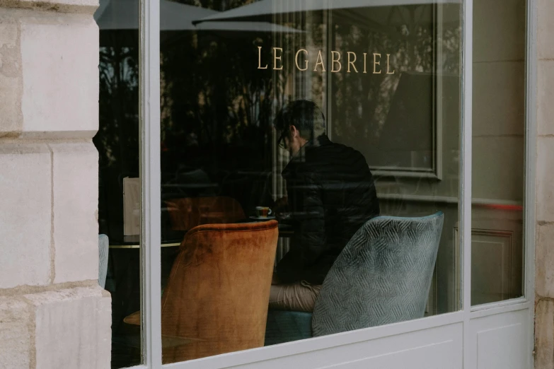 the man is sitting outside in his business window