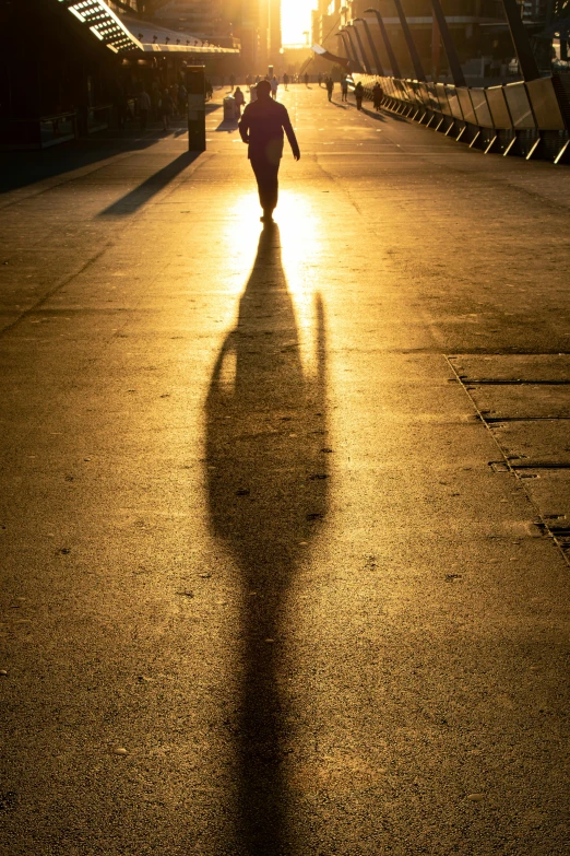 a person walking down a street under the sun