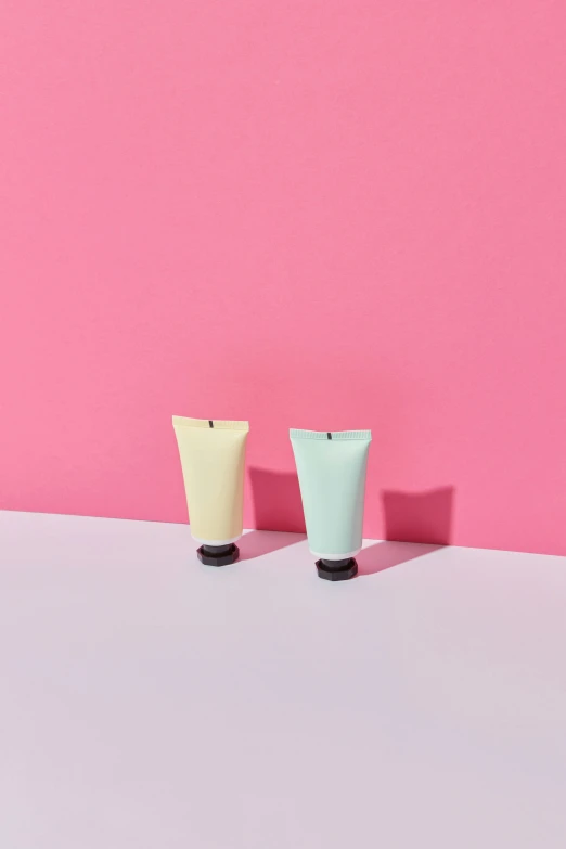 two vases sitting on a table against a pink backdrop