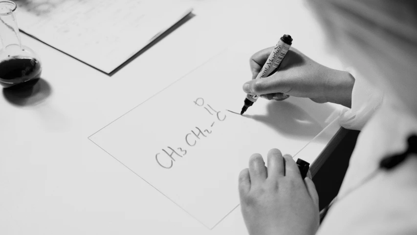 the person is writing soing on the table with her marker