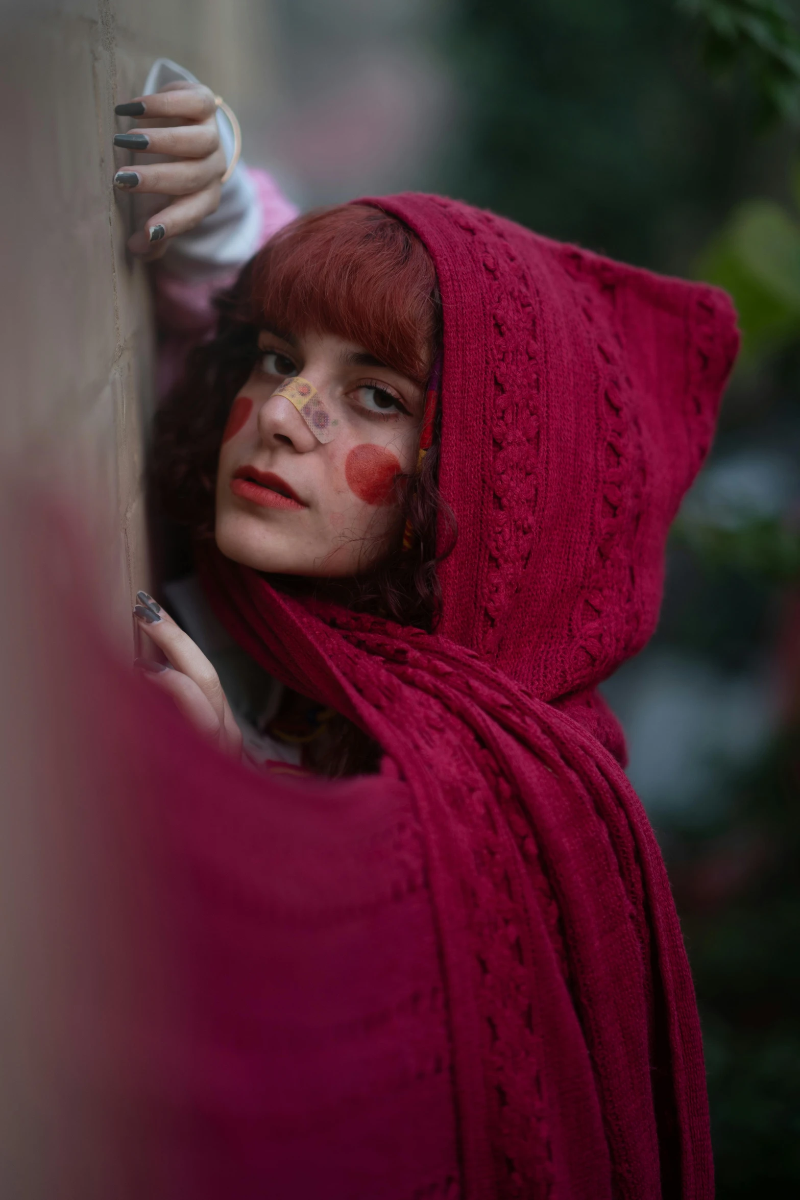 the woman is wearing a red cape and holding onto a wall