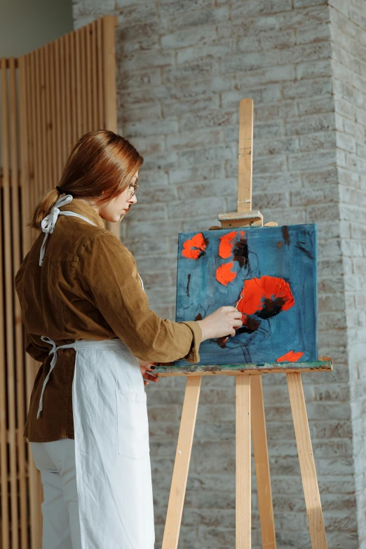 a woman holding a paint brush looking at a painting