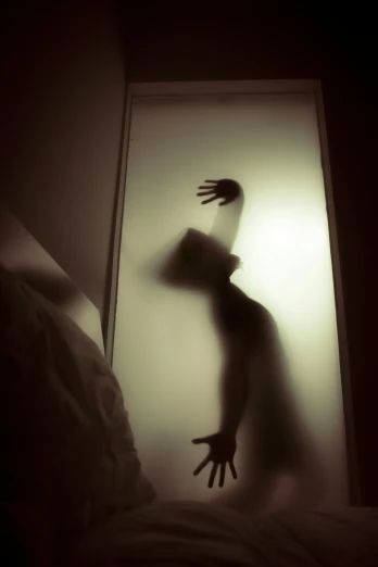 the silhouette of an outstretched woman is shown from a doorway