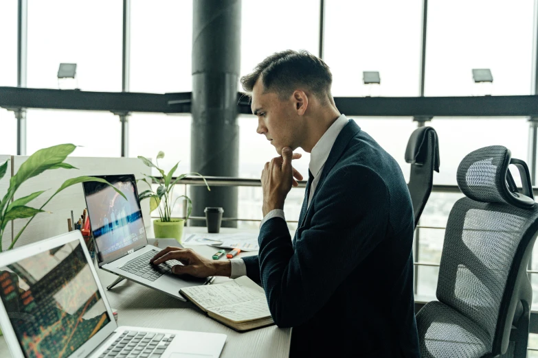 a man is sitting at a desk with his laptop on