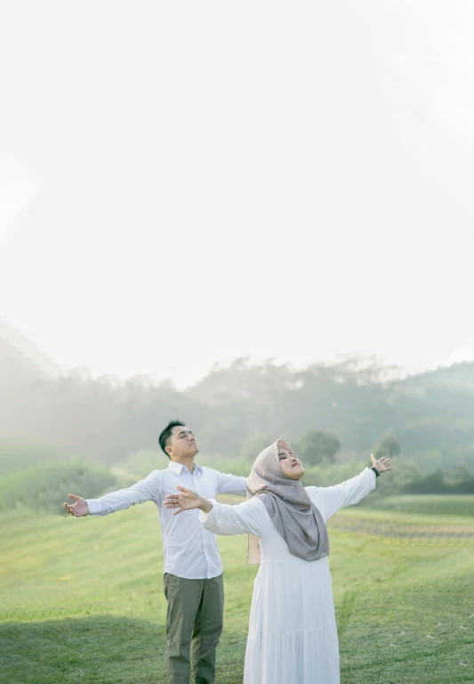 a young man and woman posing together in front of a green field