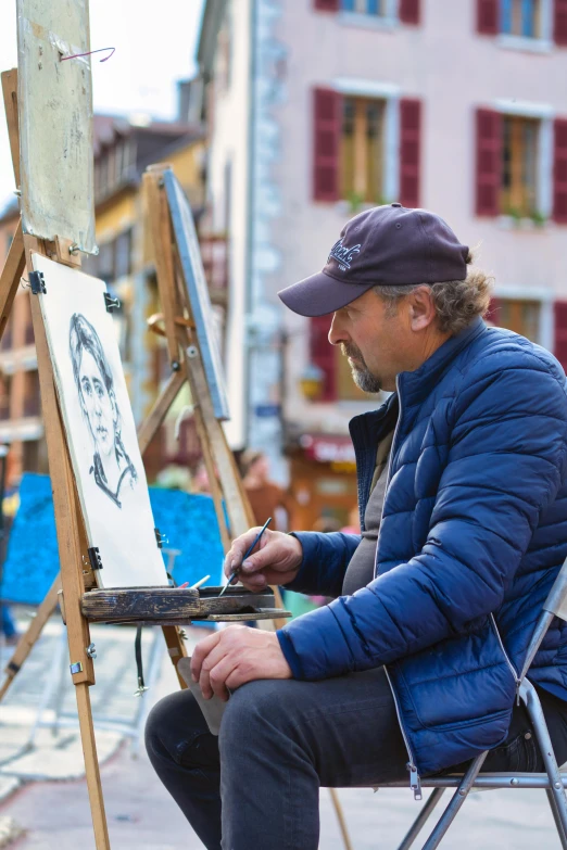a man with a cap paints in his easel