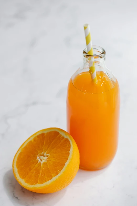 an orange juice bottle is next to a half of an orange