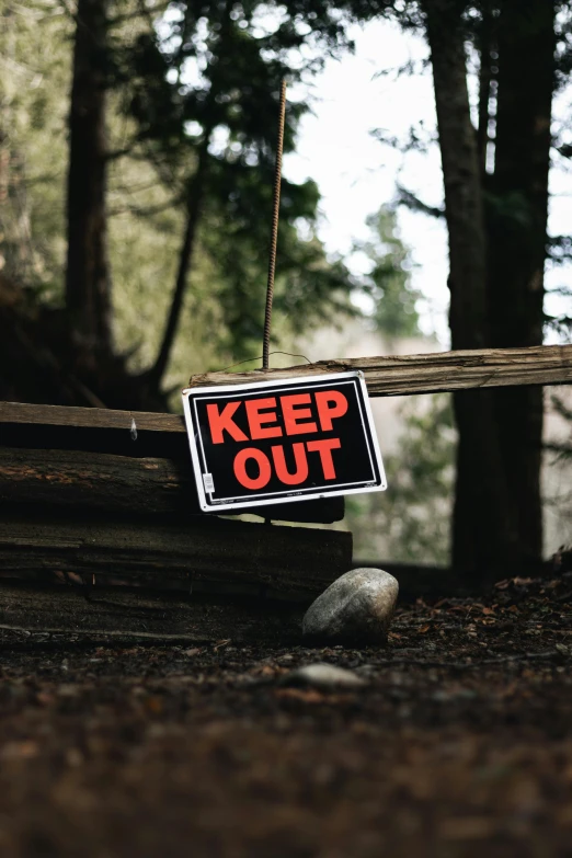 a sign that says keep out on the edge of a wooden fence