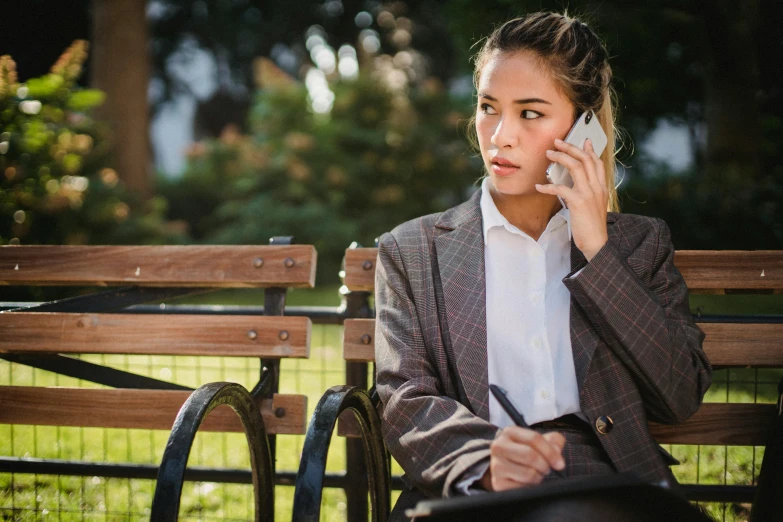 a woman sitting on a bench talking on her cell phone