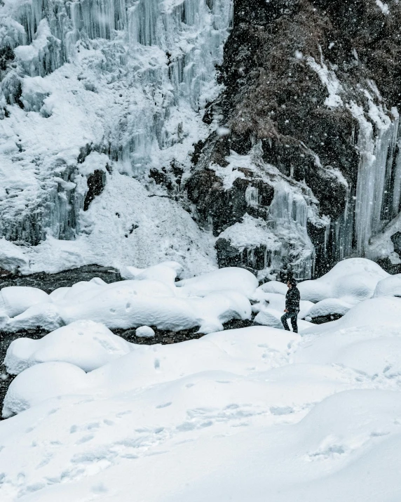 snow and ice falls with a skier standing at the top