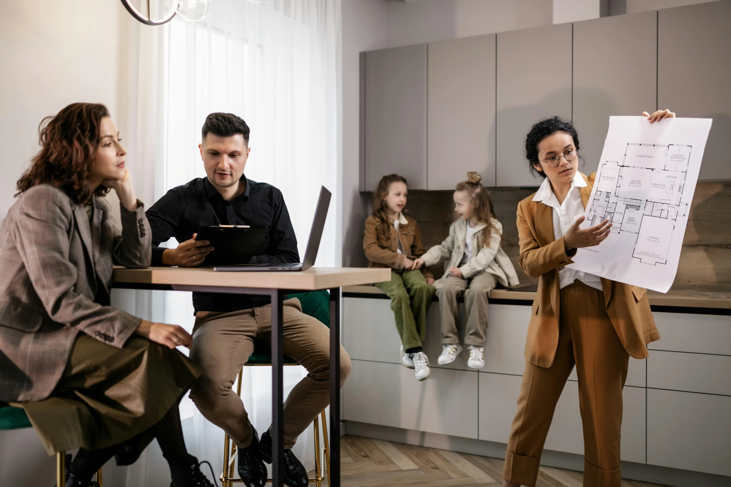 group of people sitting at table in kitchen area while writing on white paper