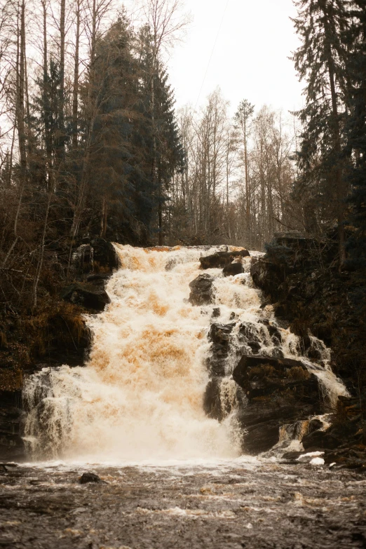 a tall waterfall surrounded by water surrounded by forest