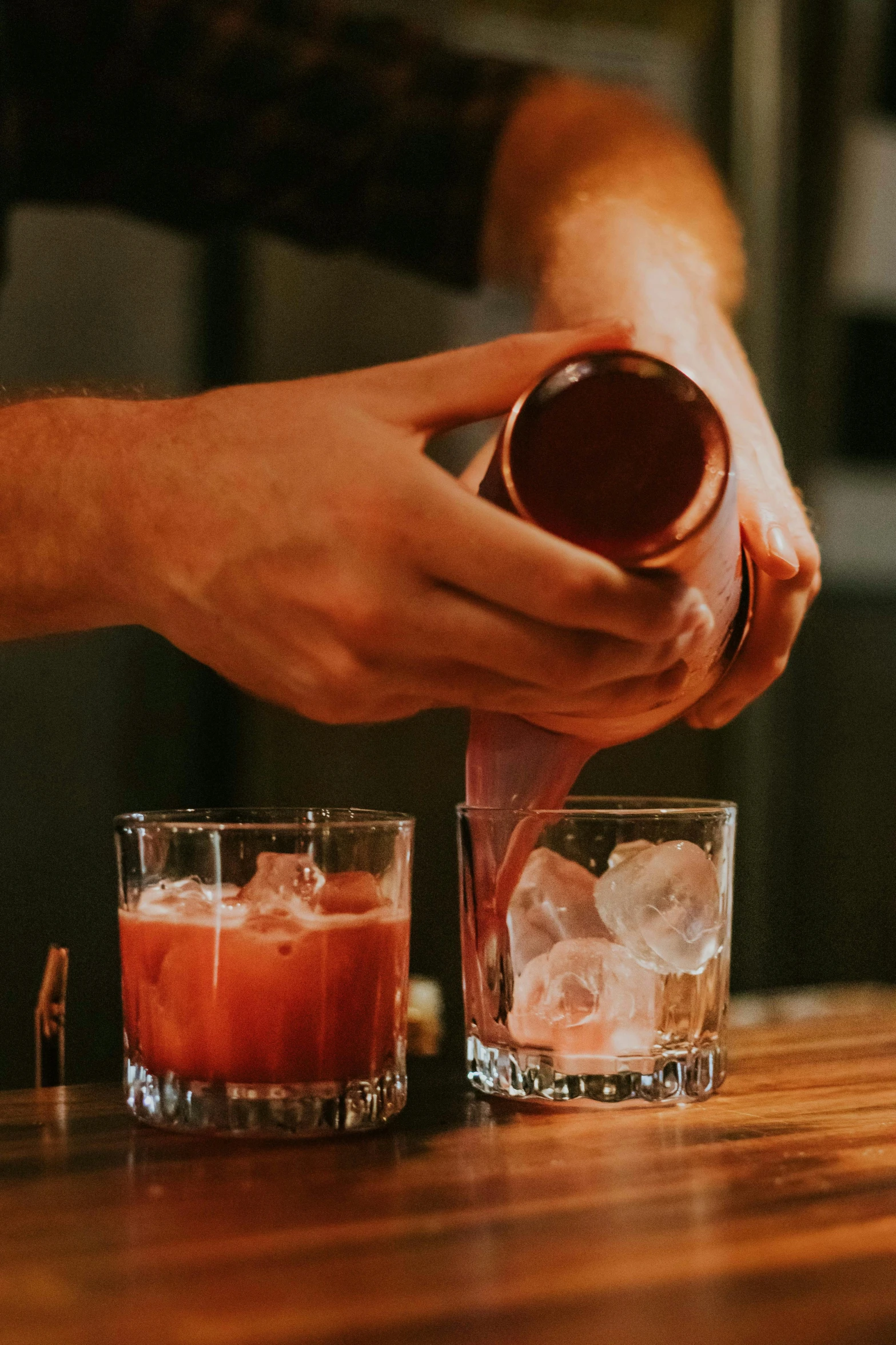 someone is adding ice to the drink in glasses