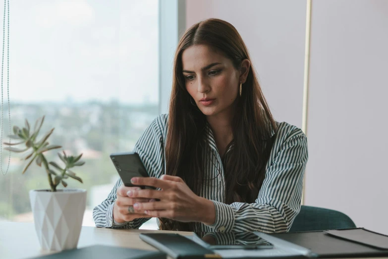 a woman on her phone sitting at a desk