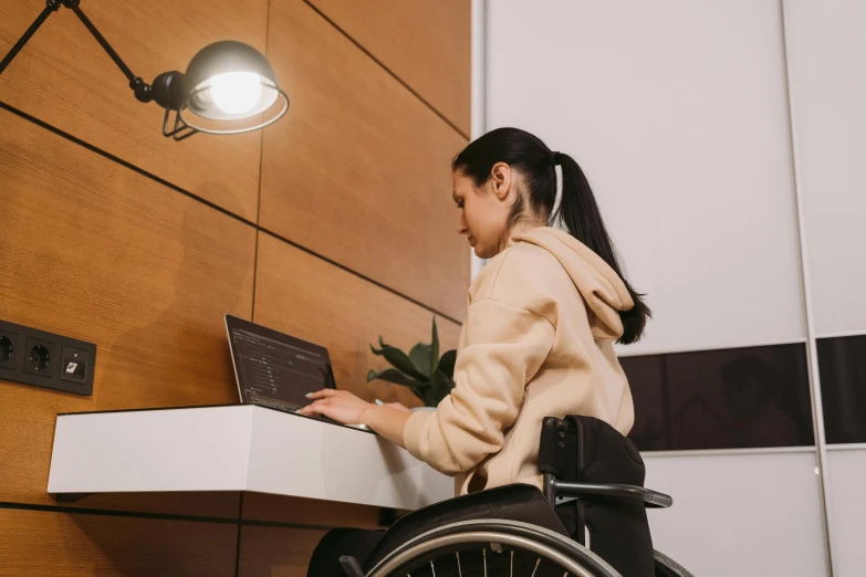 a woman sitting in a wheel chair with her laptop