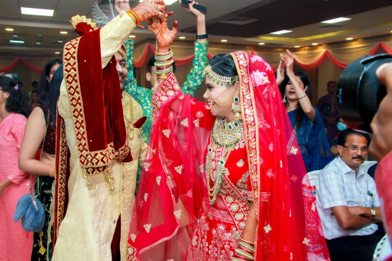 a man and woman standing in a room holding hands up