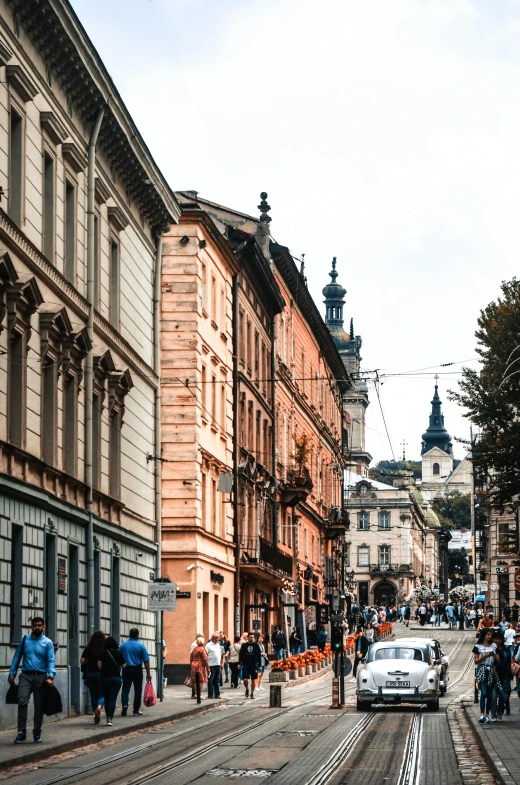 some people are walking down a street while a car is in the road