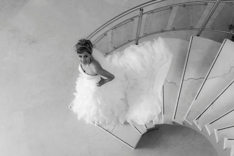 a woman is posing on top of a spiral staircase