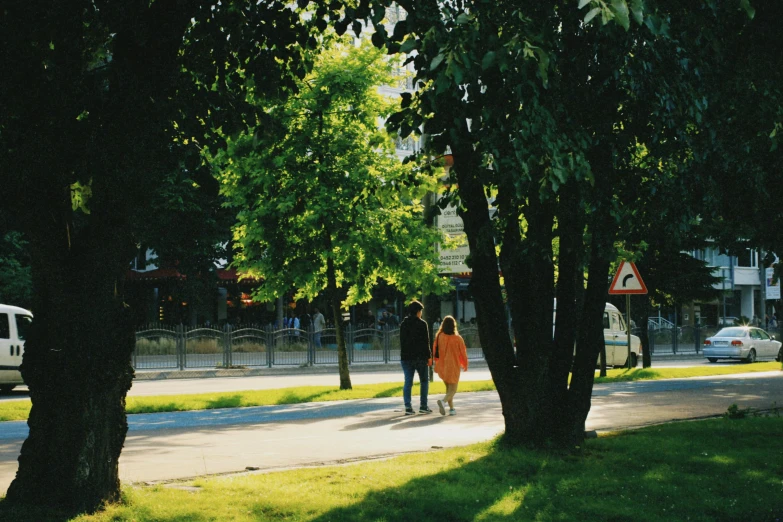 a group of people walk down the street with the sun shining