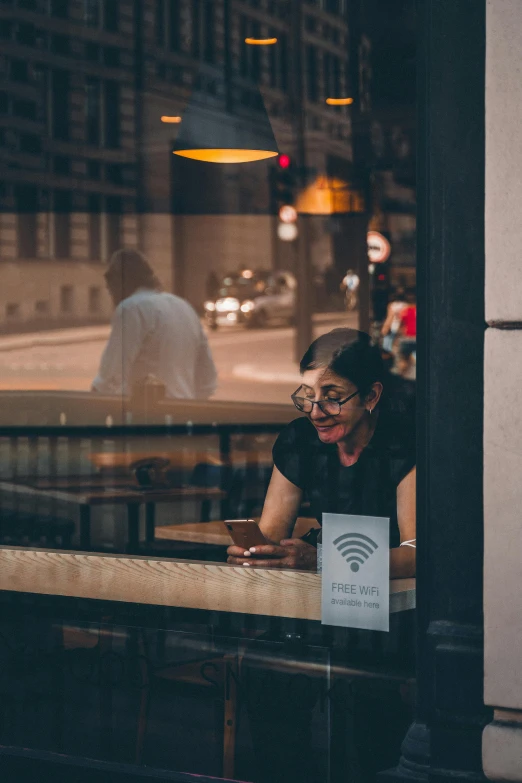 the woman behind the table is enjoying her drink