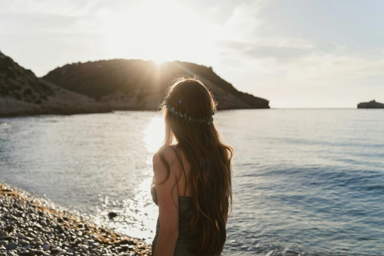 a girl standing on the beach looking out at the ocean