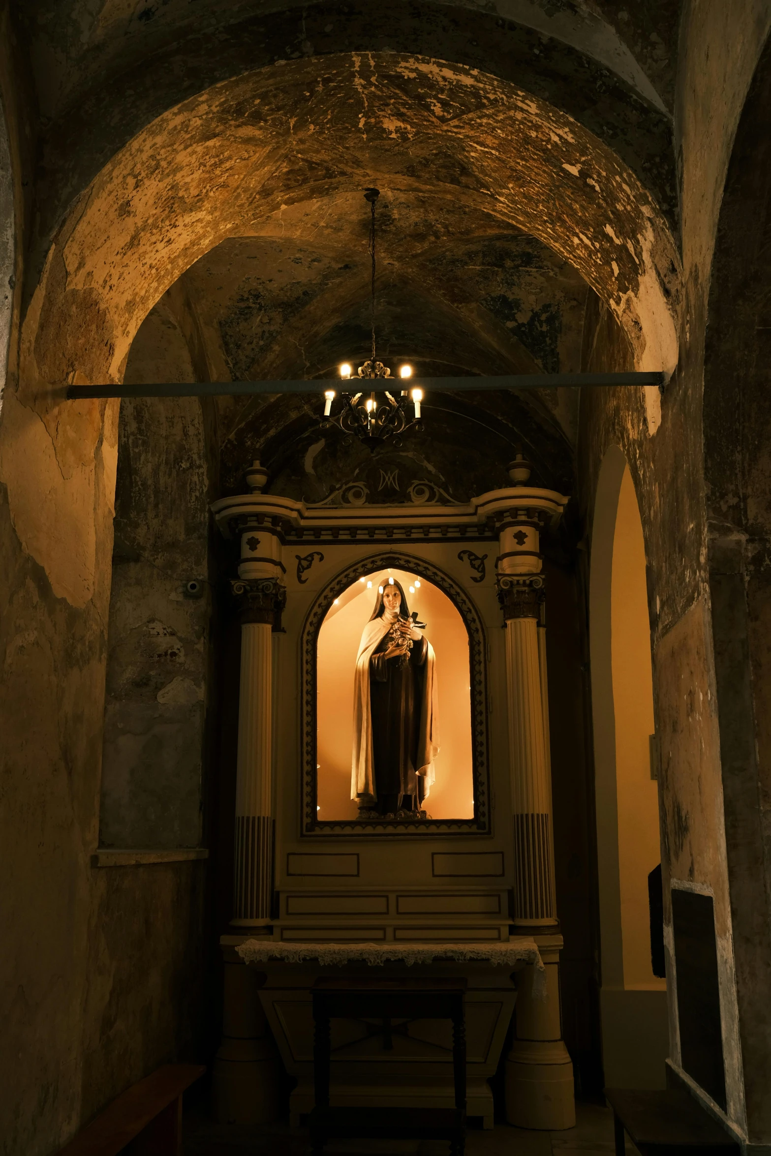 a very large statue sitting under a light in a stone wall