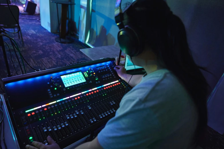 a man wearing headphones at a sound board in the dark