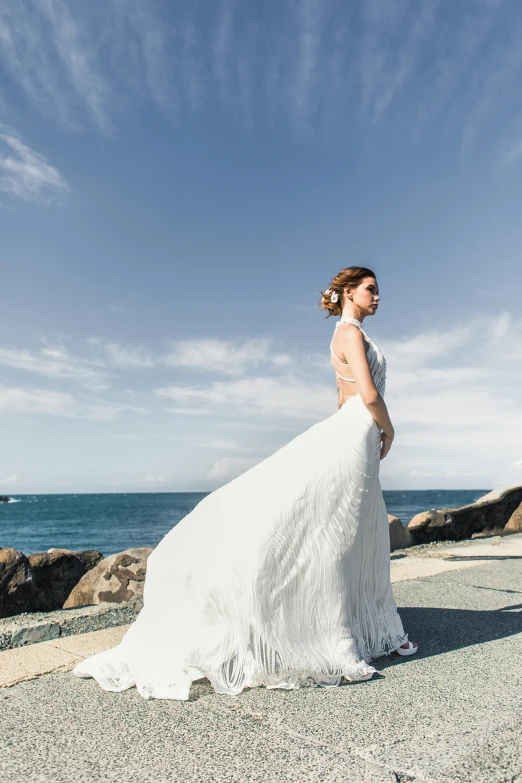 a bride in a lace wedding gown poses on the beach