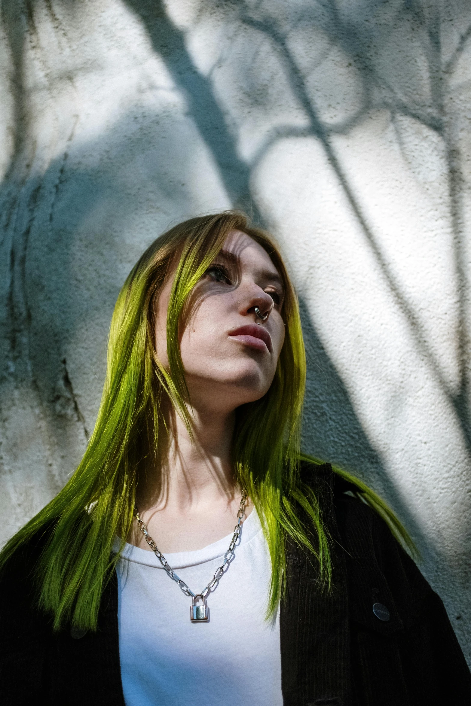 a girl with green hair is standing in front of a white wall