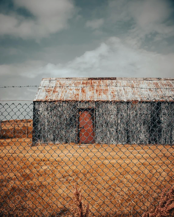 a farm building behind a fence with a red door