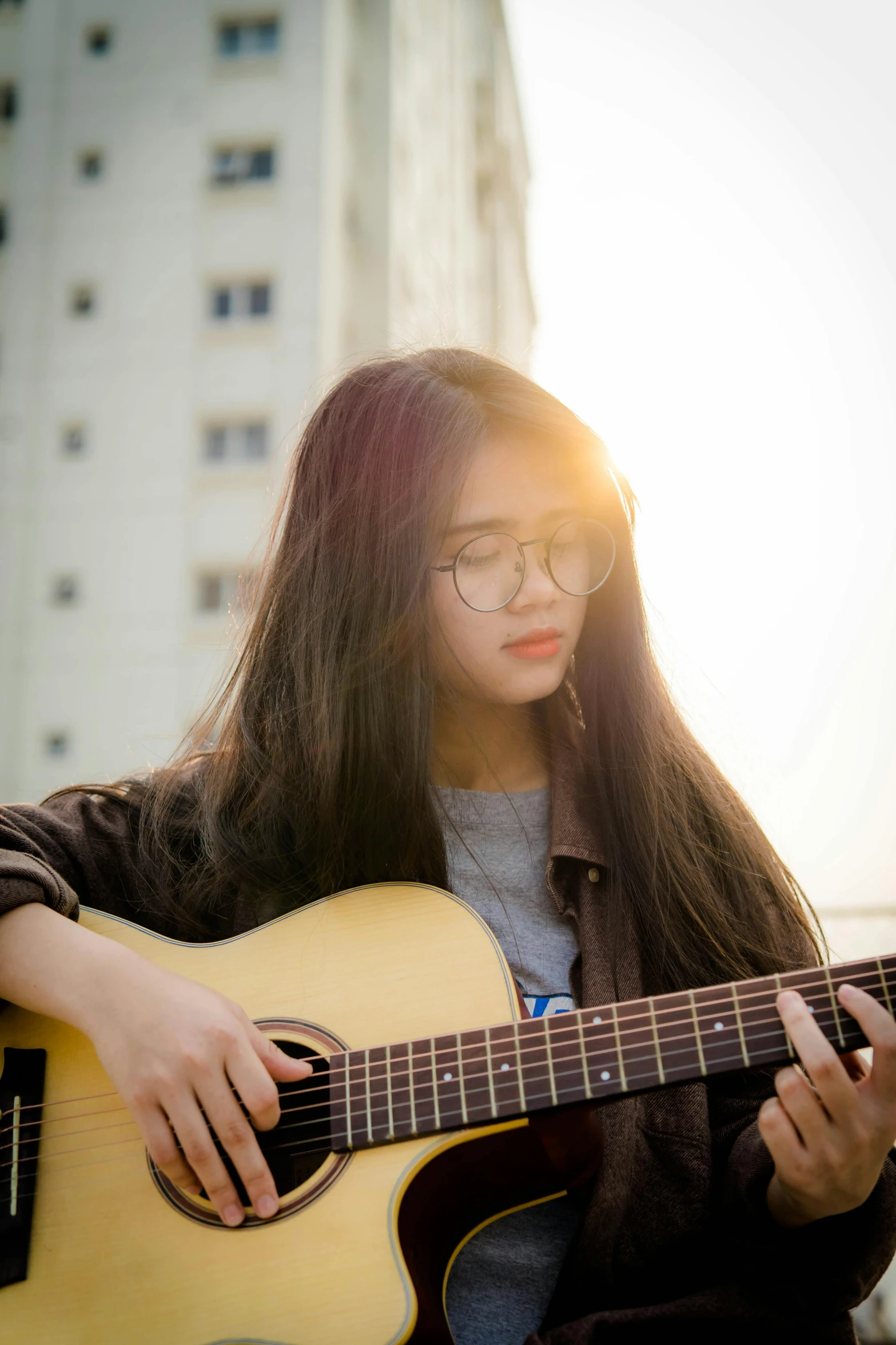 a young asian girl plays the guitar in the city