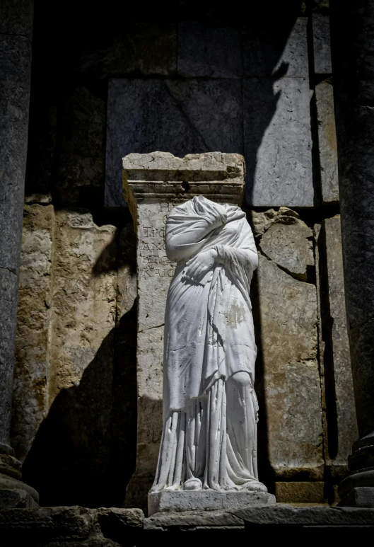 a sculpture of woman in white cloth on some stone