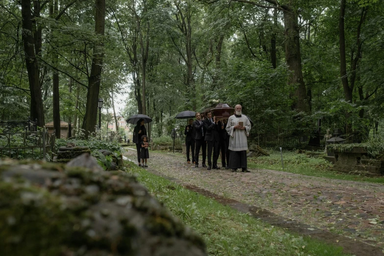 several people walking in the woods holding umbrellas