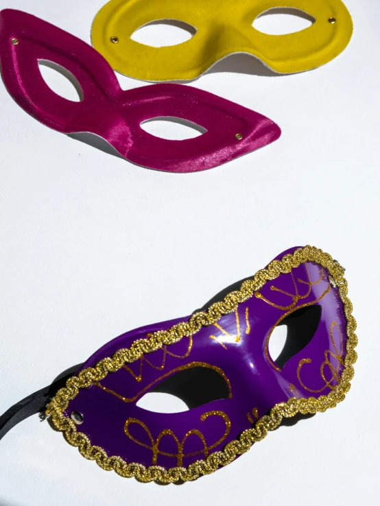 three masquerade masks are shown on a table