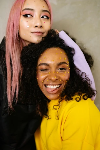 two people who are standing up and one has makeup applied to her face