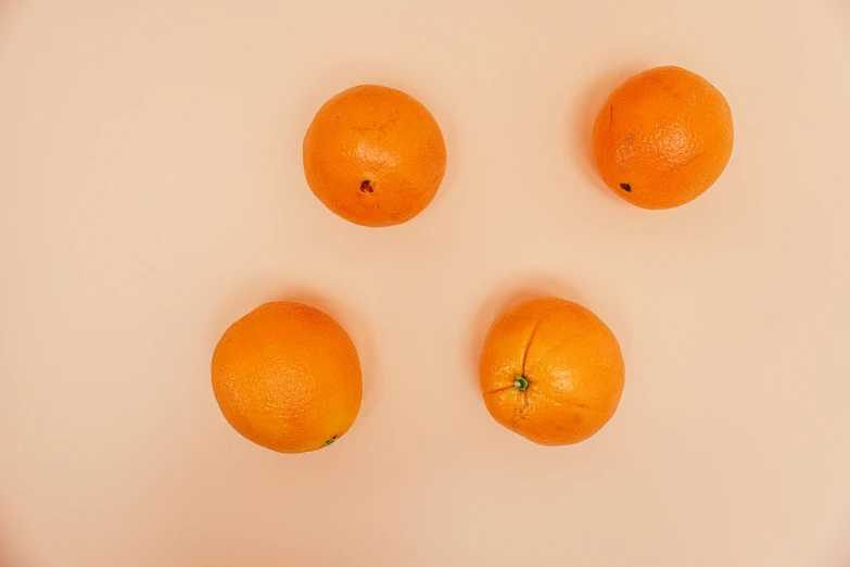 four oranges on top of a white surface