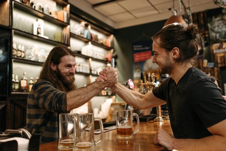 a couple of men sitting at a bar shaking hands