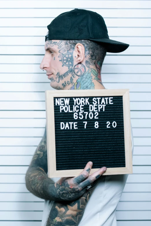 a tattooed man holding a sign that reads police dept date