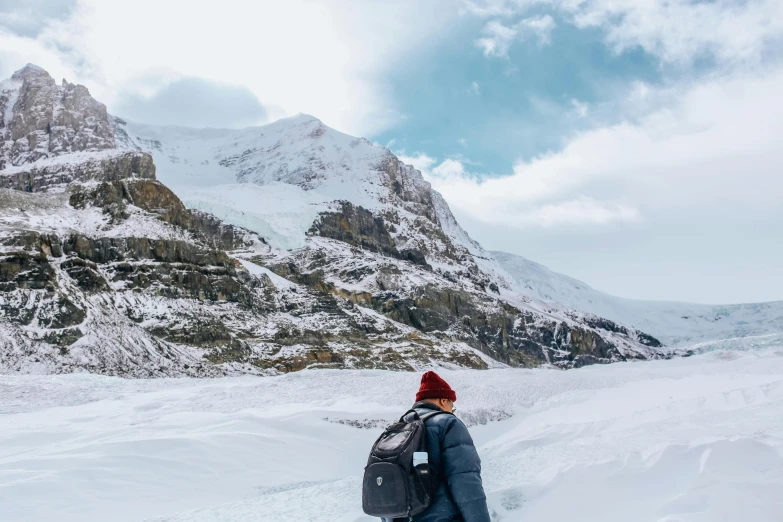 person in red hat walking along snow covered slope