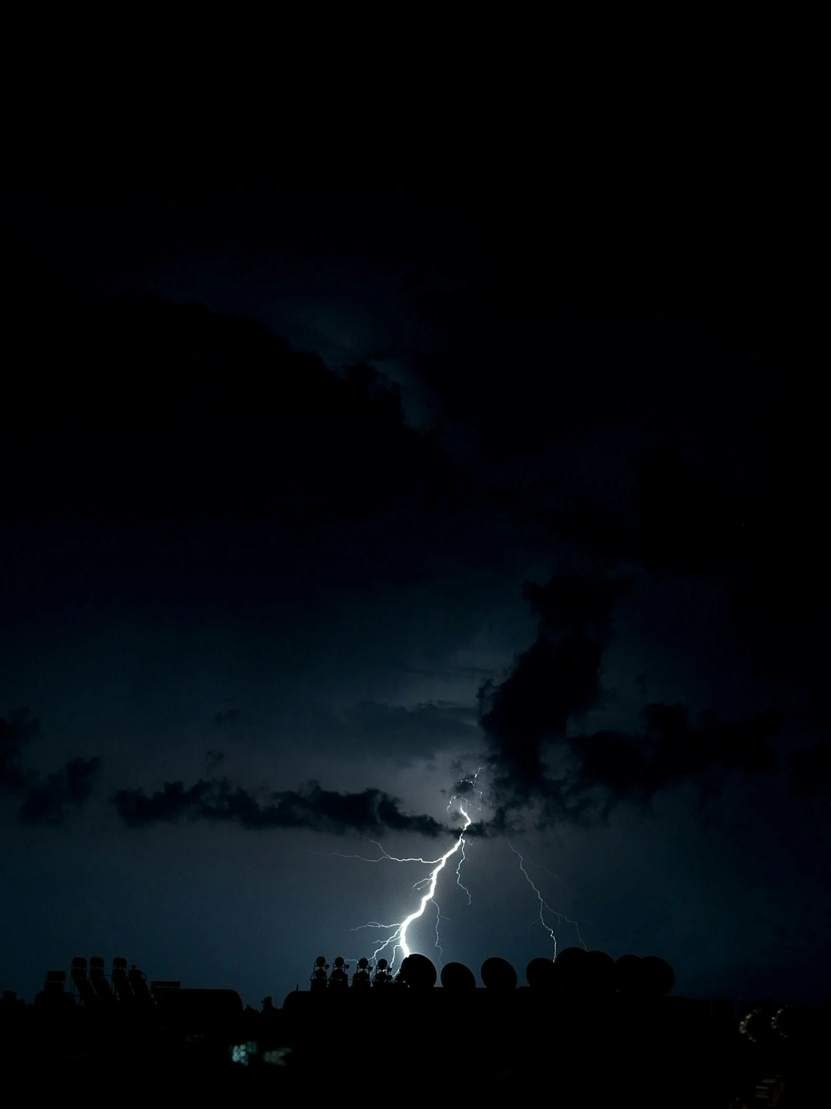 a dark sky filled with lightning and very tall buildings