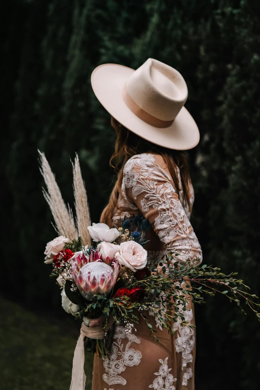 a woman in a cowboy hat holds a large bouquet
