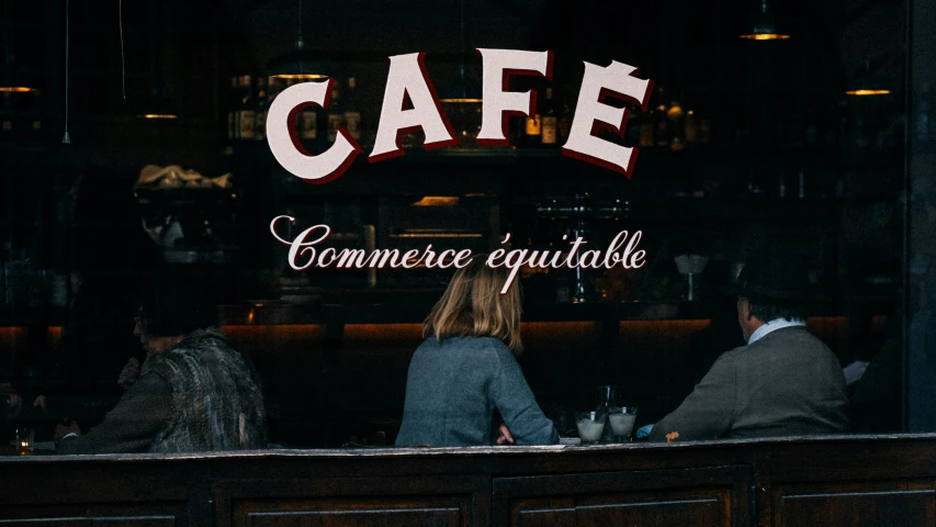two people sitting at a table in front of a cafe