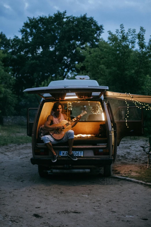 two people playing guitar in the back of a van